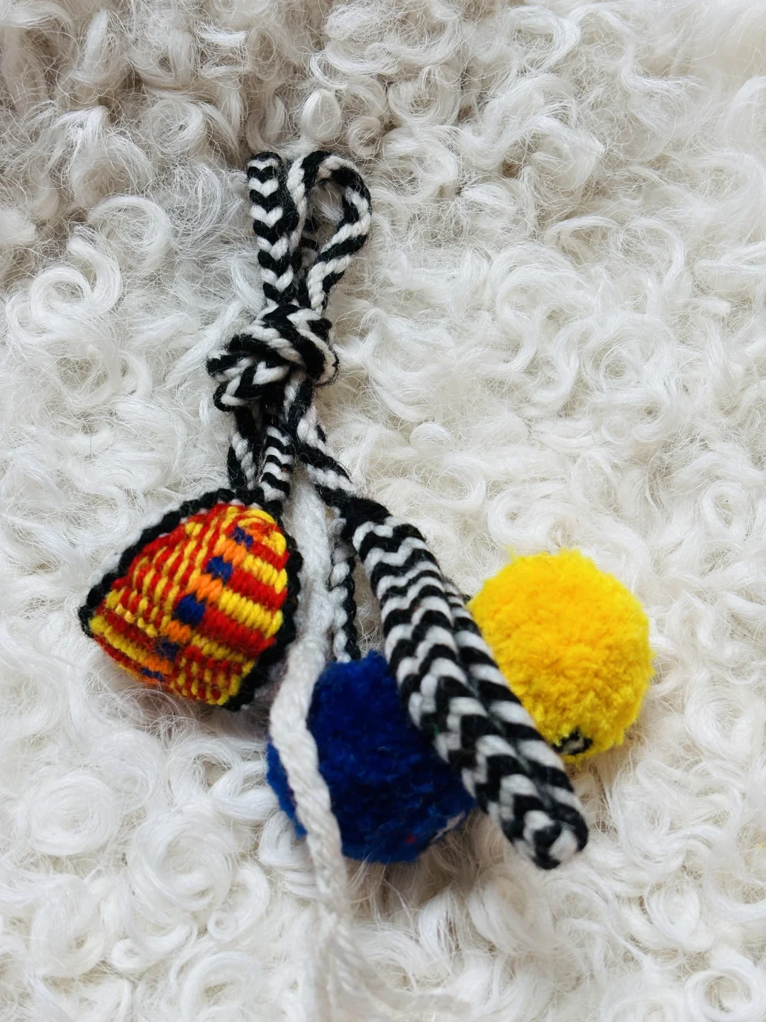 A hand-knotted wurdoo with a yellow pom-pom resting on snow at altitude